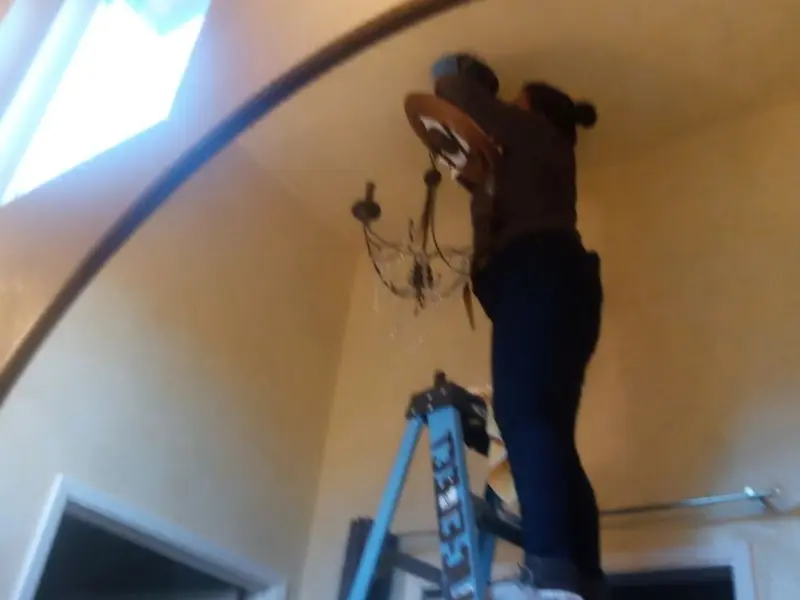 Electrician installing a chandelier in a Dix residence